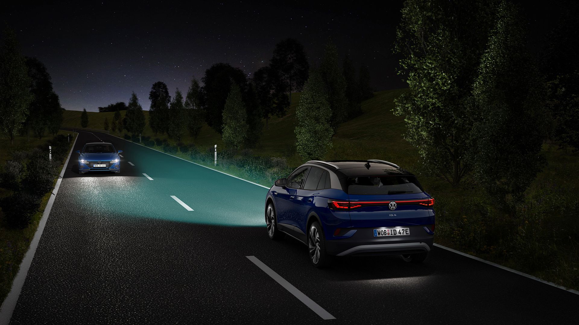 Um VW ID.4 azul segue ao longo de uma estrada noturna com as luzes ligadas.