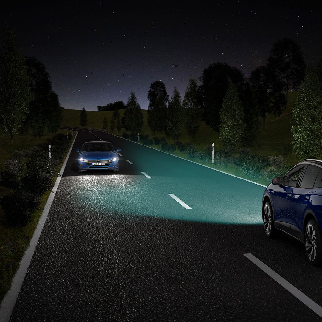 Um VW ID.4 azul segue ao longo de uma estrada noturna com as luzes ligadas.