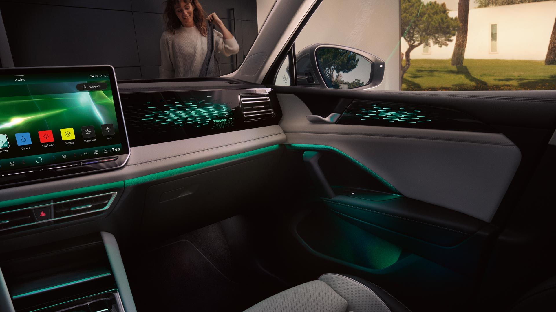 Vista interior do VW Tiguan, o ecrã a cores mostra as definições da iluminação ambiente opcional, o habitáculo é iluminado a verde.