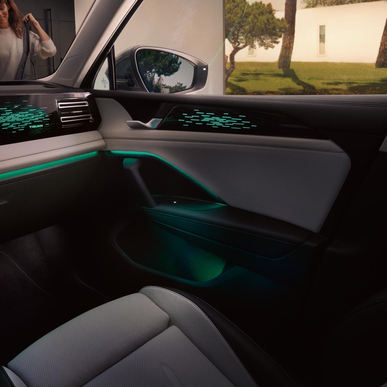 Vista interior do VW Tiguan, o ecrã a cores mostra as definições da iluminação ambiente opcional, o habitáculo é iluminado a verde.