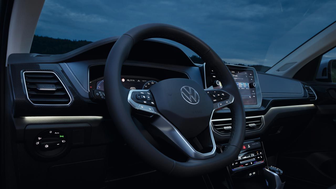 Vista noturna detalhada para o cockpit do VW T-Cross com foco na iluminação ambiente dinâmica em branco