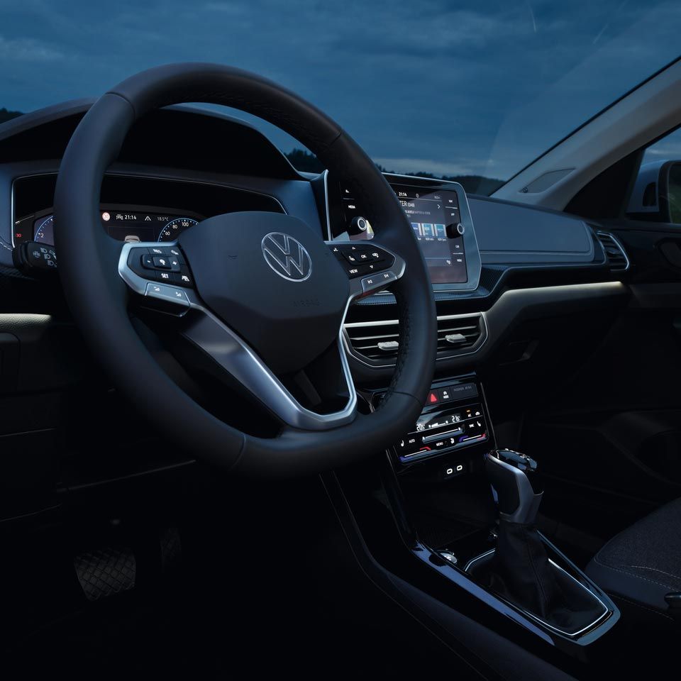 Vista noturna detalhada para o cockpit do VW T-Cross com foco na iluminação ambiente dinâmica em branco