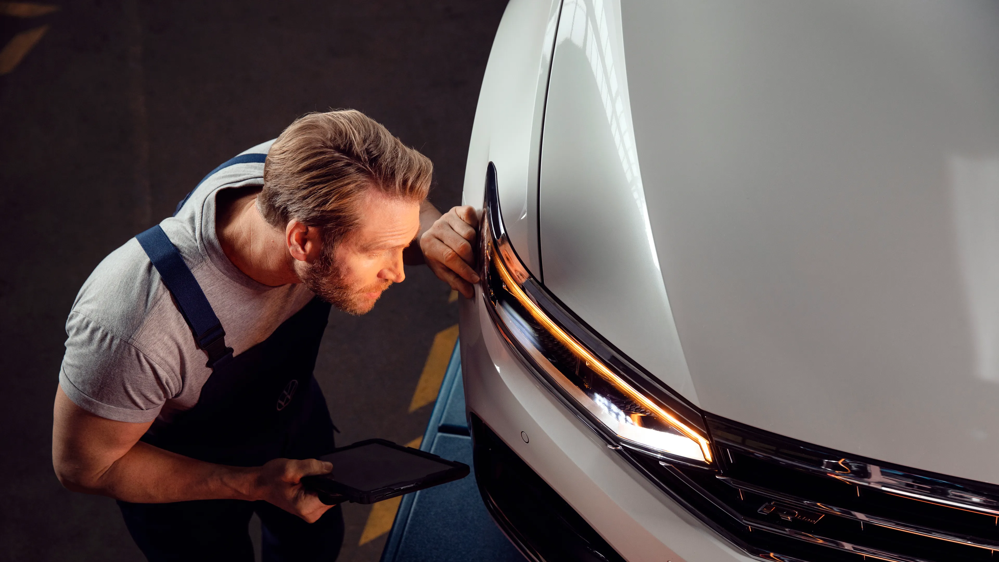 VW Service Mitarbeiter prüft den Frontscheinwerfer