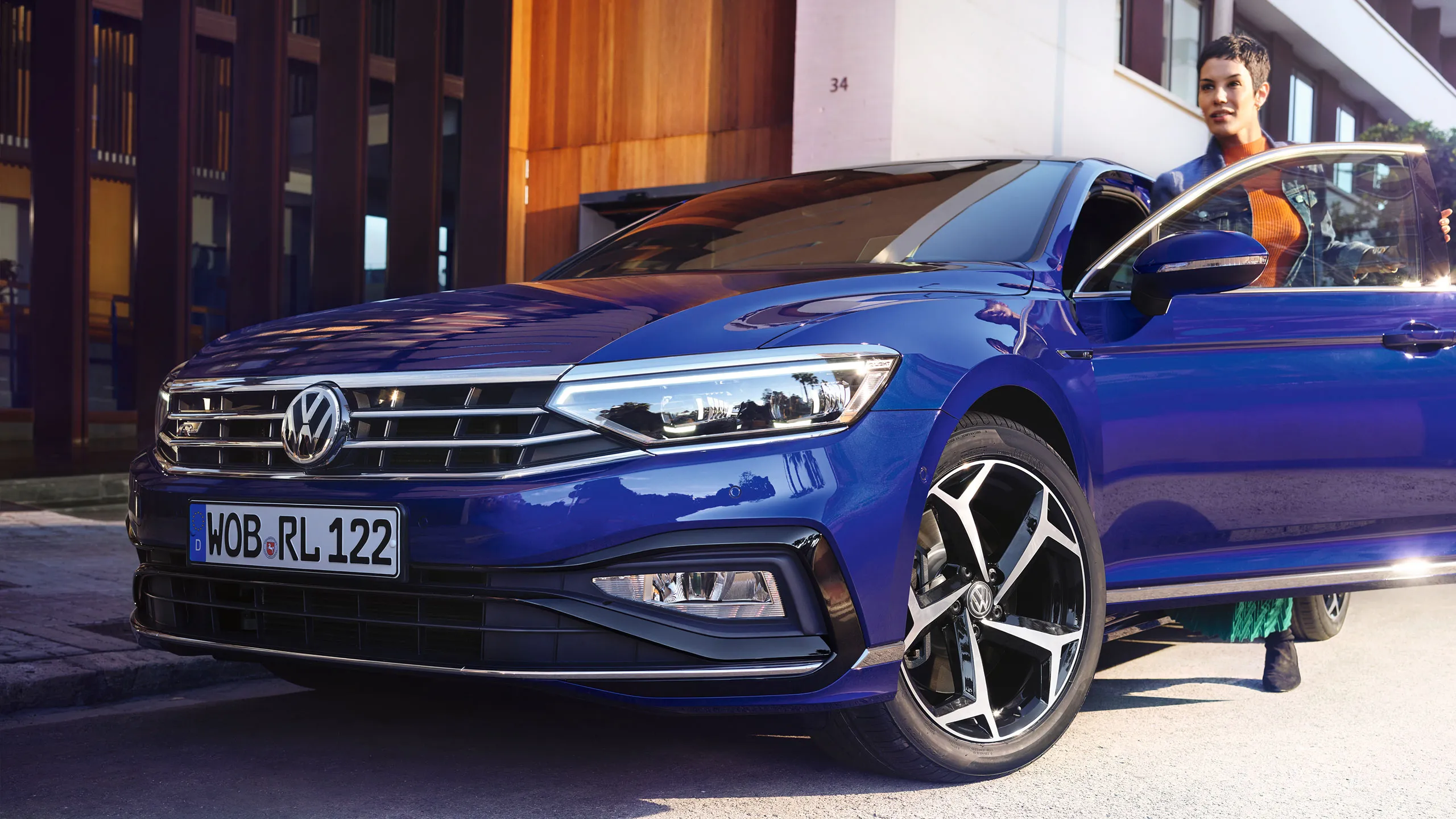 Uma mulher sai da sua carrinha azul VW Passat R-Line