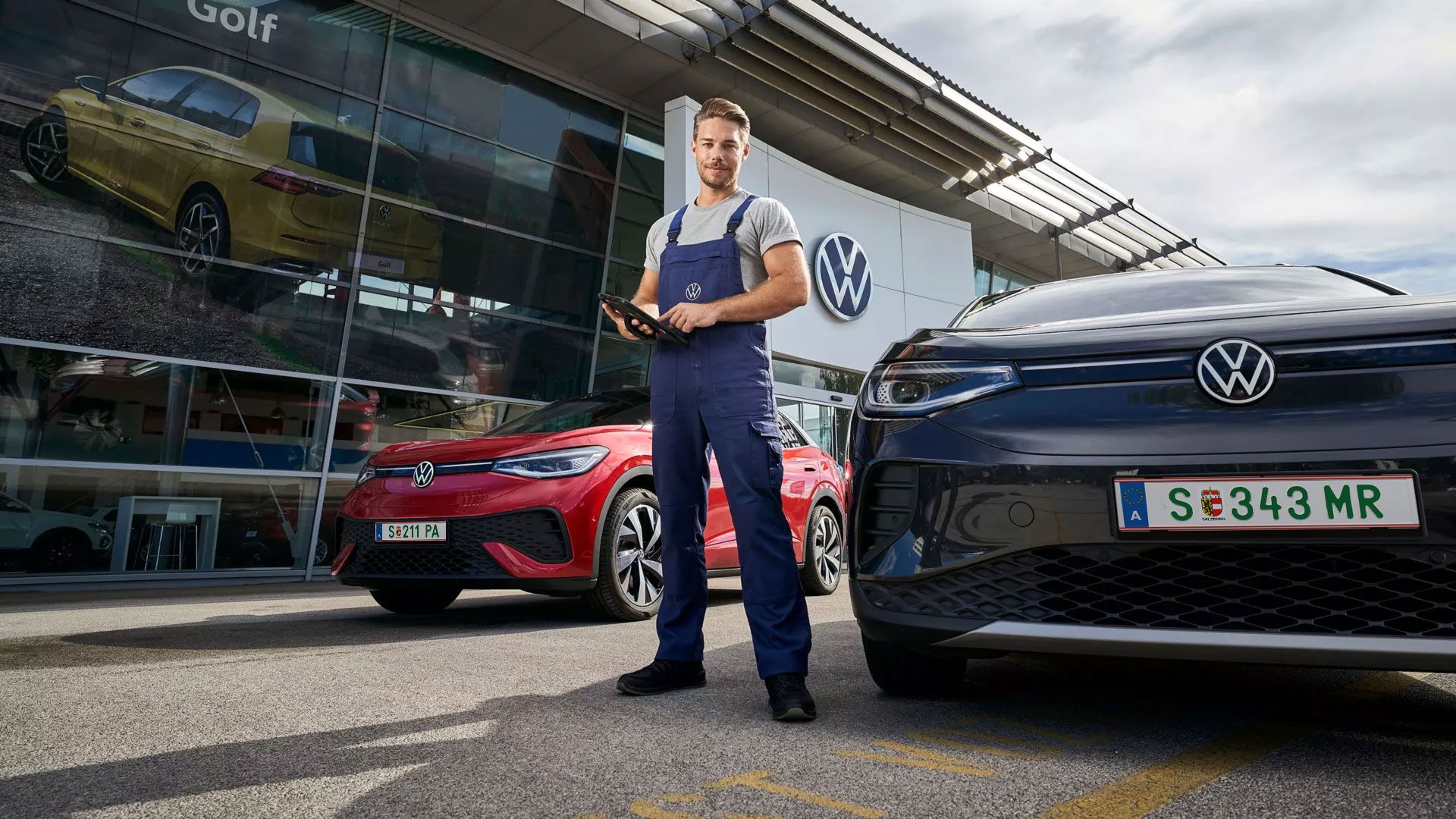 Ein VW Service Techniker mit Tablet steht zwischen zwei ID's