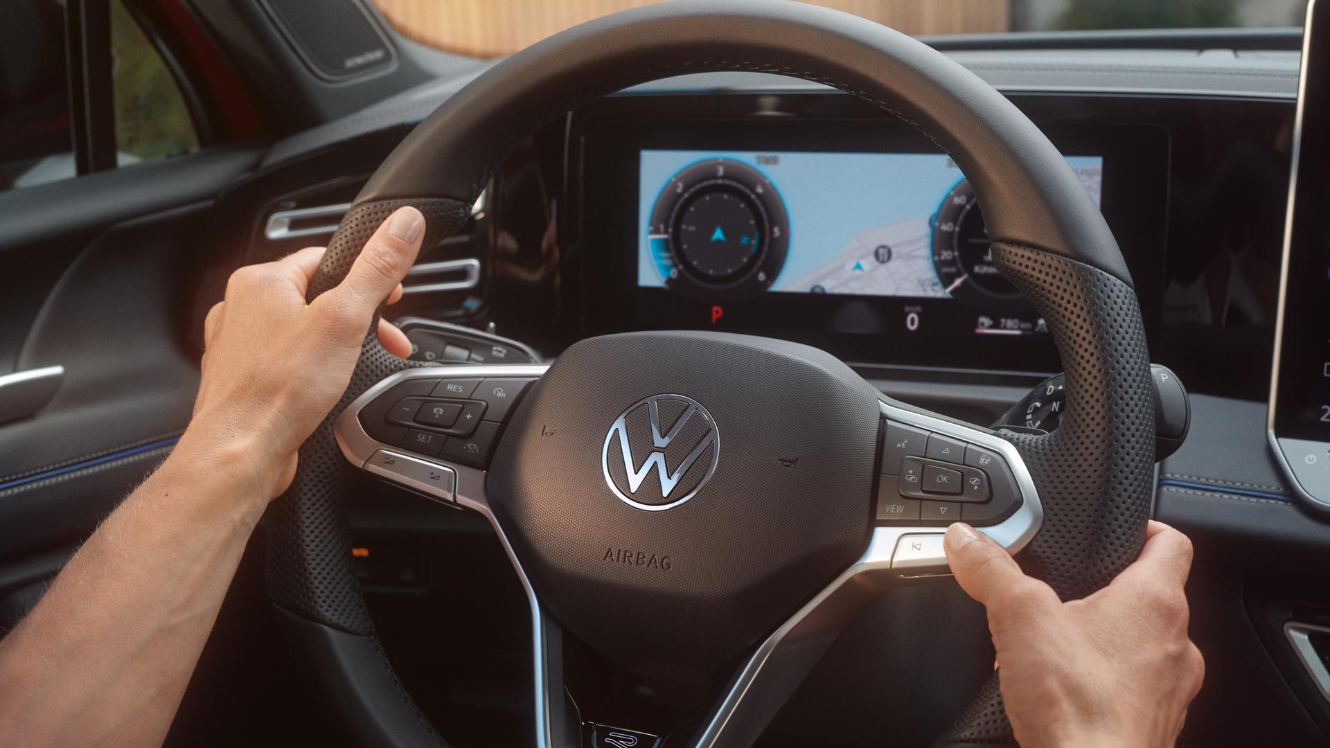 Vista detalhada do cockpit de um VW Tiguan. Duas mãos agarram o volante.