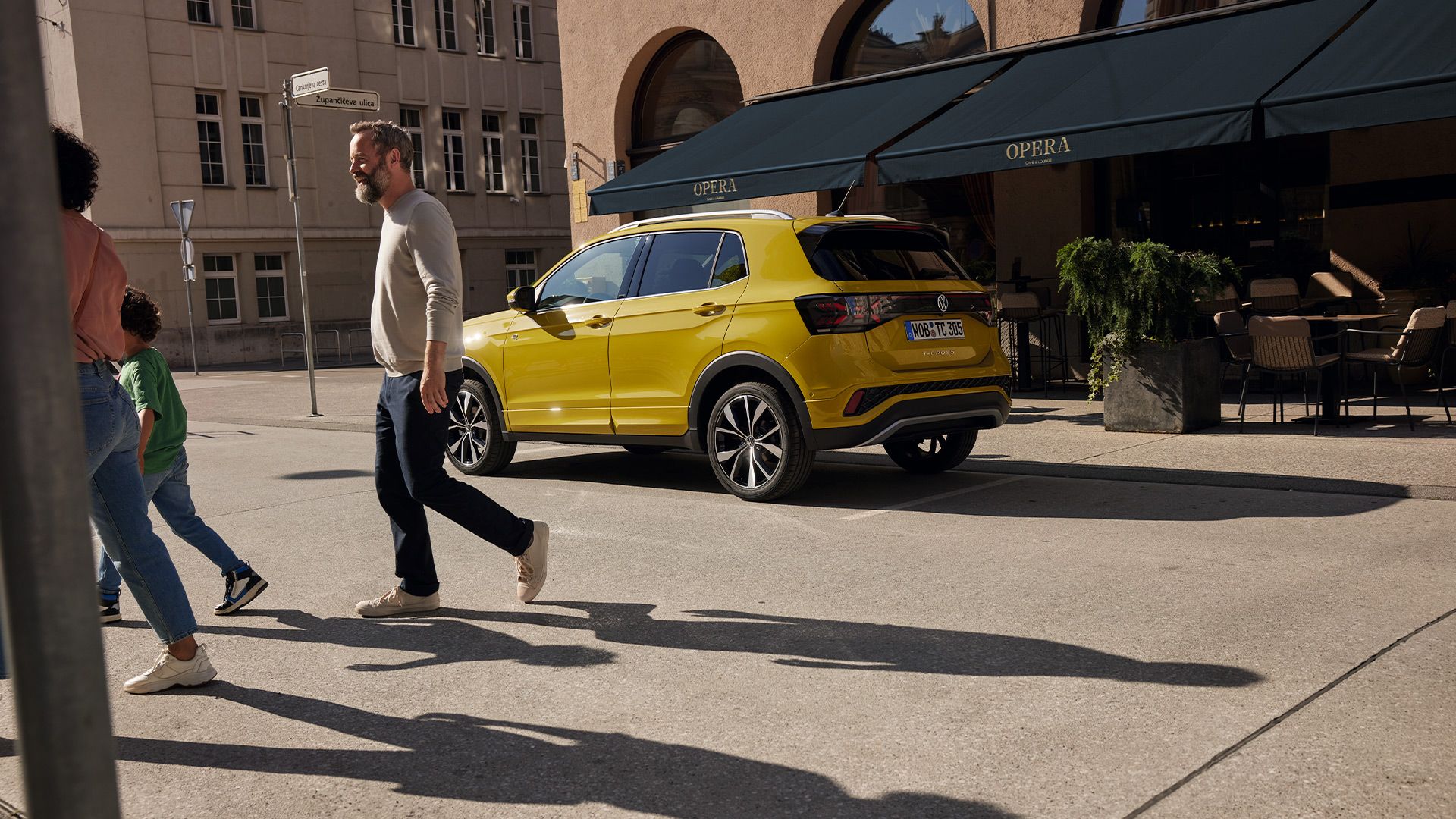 Um homem afasta-se de um VW T-Cross amarelo. Em segundo plano encontra-se a esplanada de um café.