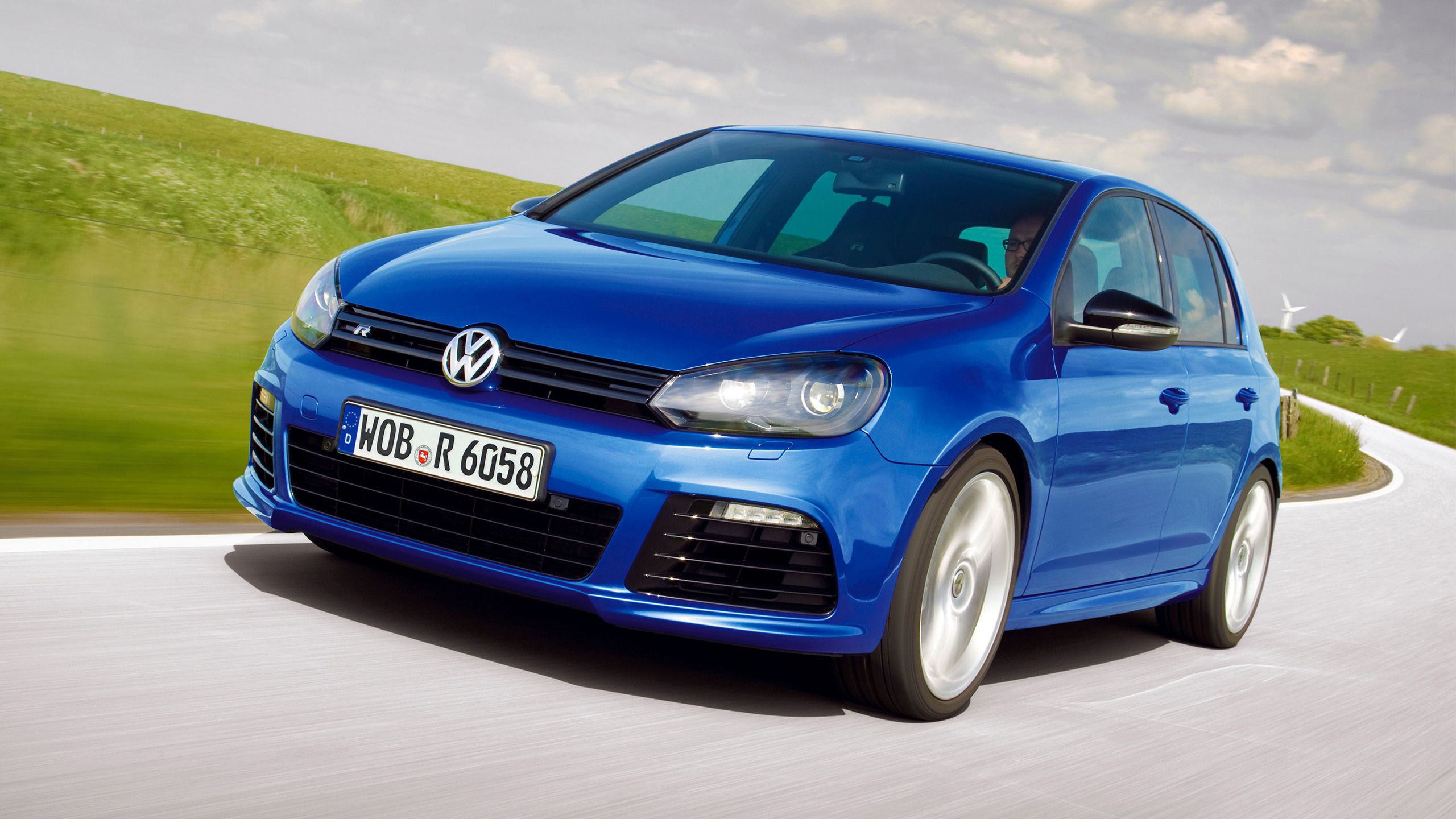 Um homem está a conduzir com o seu Volkswagen 6 R azul numa estrada