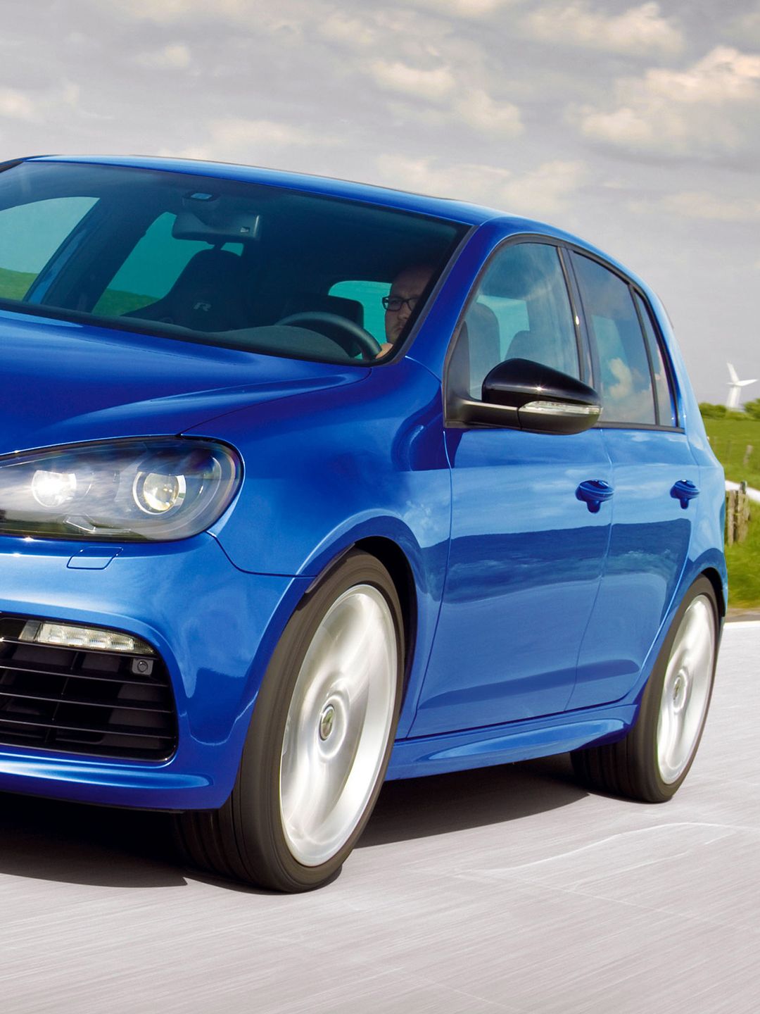 Um homem está a conduzir com o seu Volkswagen 6 R azul numa estrada