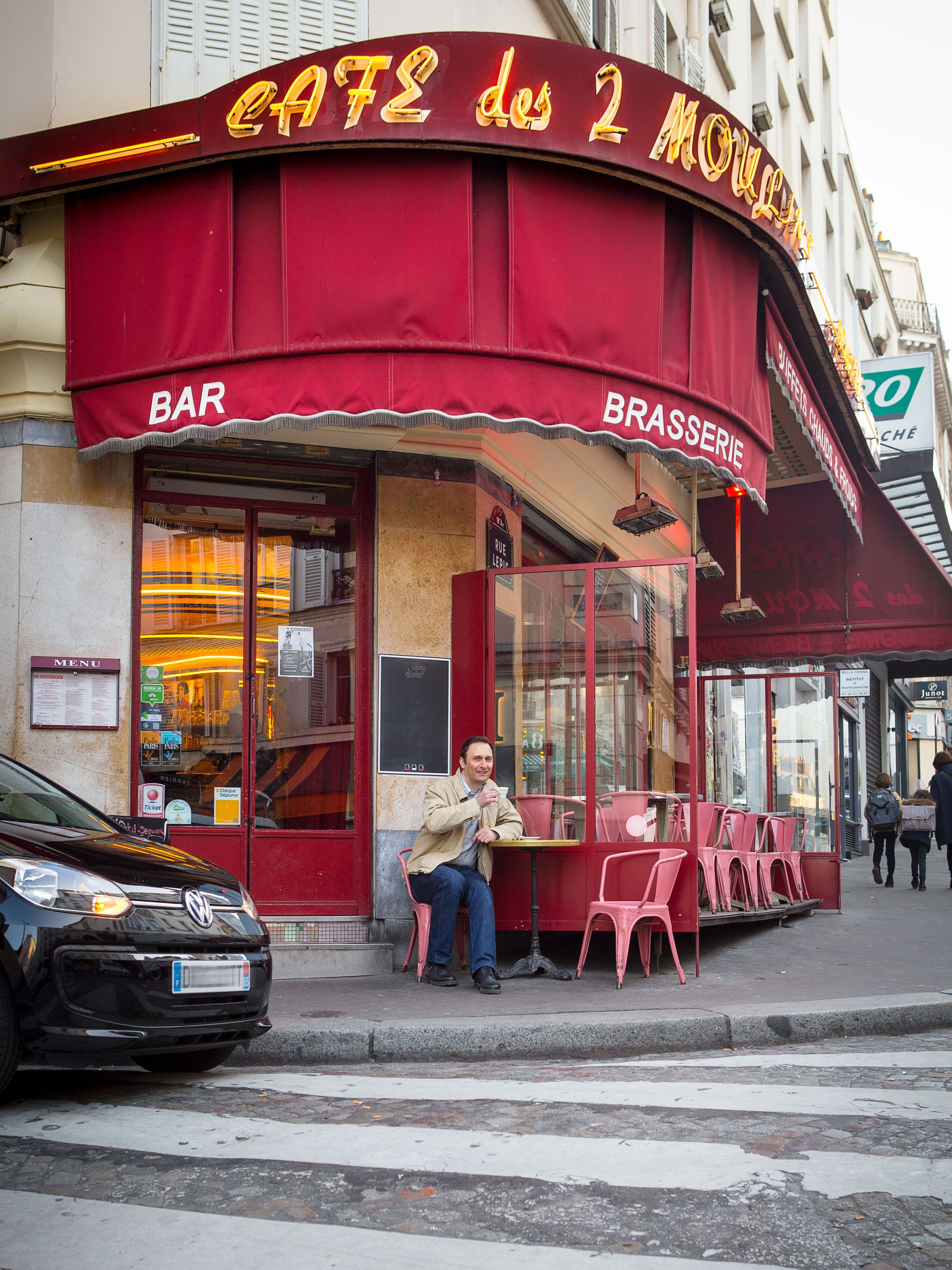 Alexandre Marie sitzt vor einem Café, sein e-up! ist neben ihm geparkt