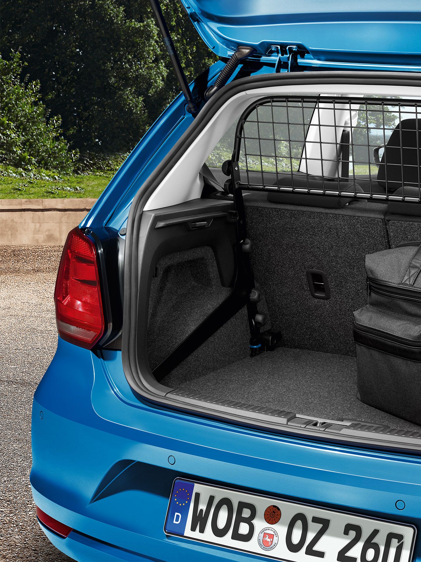 Uma vista detalhada de uma grelha de bagagem e um grande saco no porta-bagagens de um VW Polo 5 azul - Acessórios Volkswagen