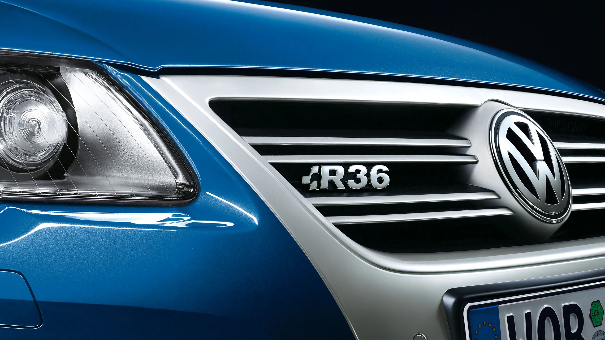 Vista detalhada de um carro VW Passat R36 azul com o emblema "R36" na grelha do radiador.