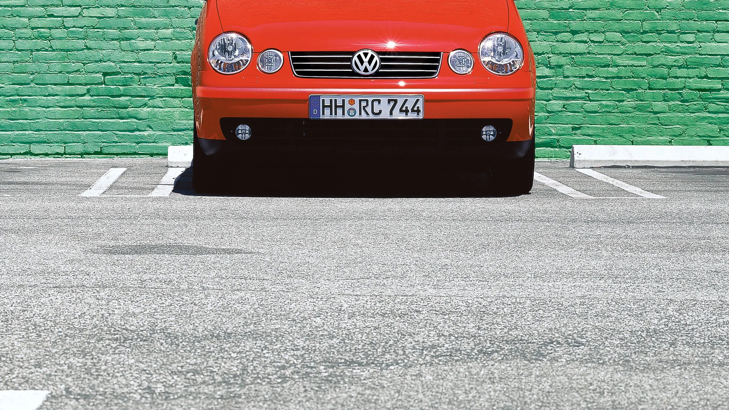 Um estacionamento VW Polo 4 tipo 9N1 vermelho em frente a uma parede verde