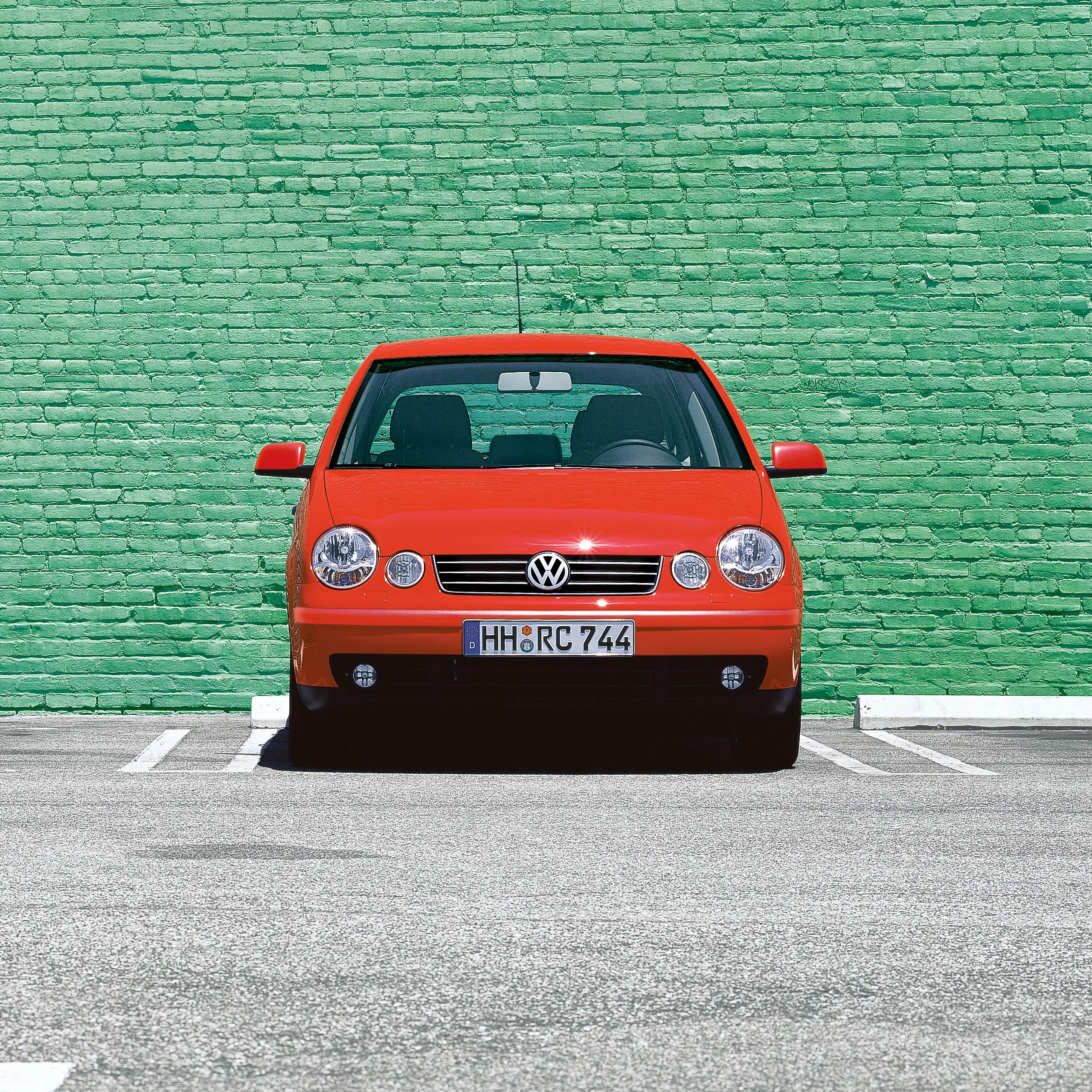 Um estacionamento VW Polo 4 tipo 9N1 vermelho em frente a uma parede verde