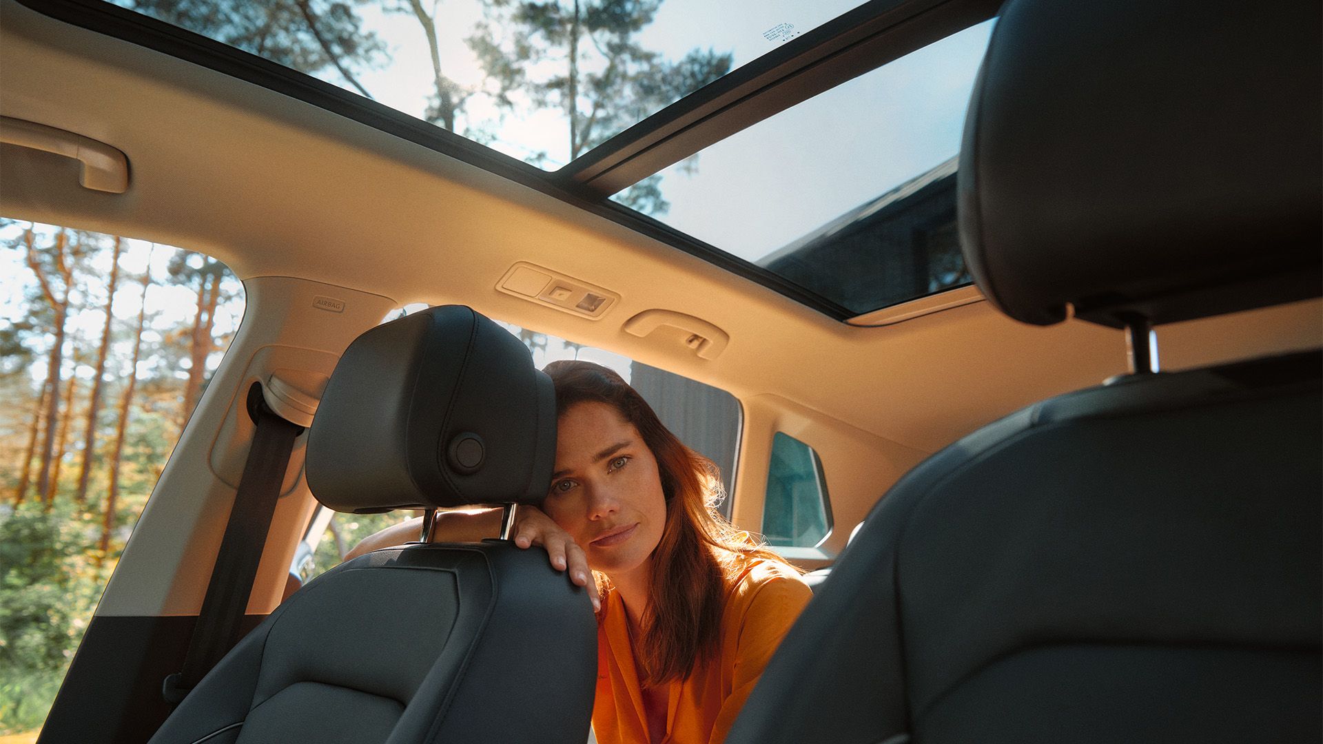 Mulher sentada no banco traseiro do VW ID.3, encostada ao encosto do banco do passageiro e a olhar para o observador