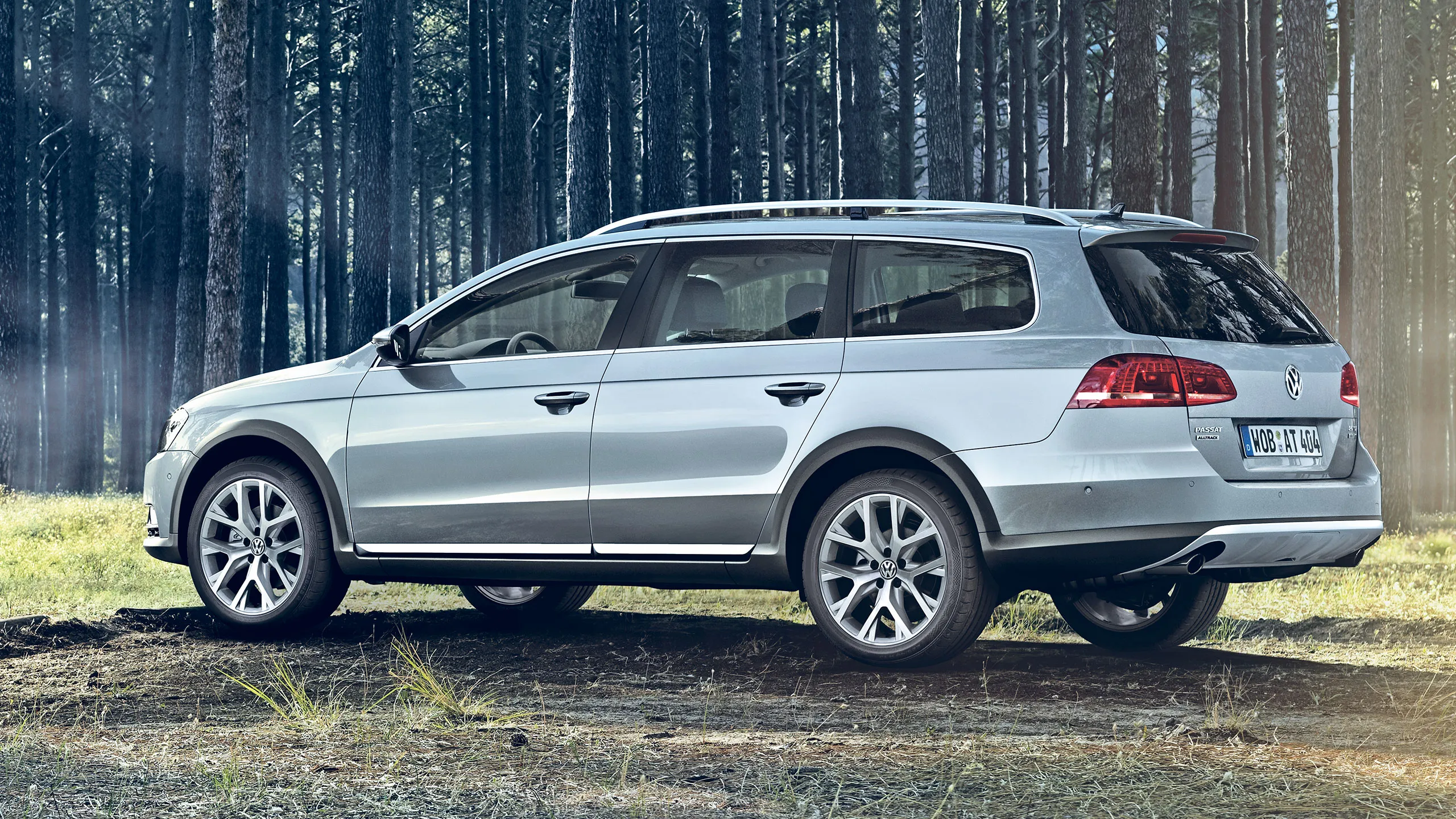 Um carro Passat B7 prateado estacionado num caminho sinuoso na floresta.