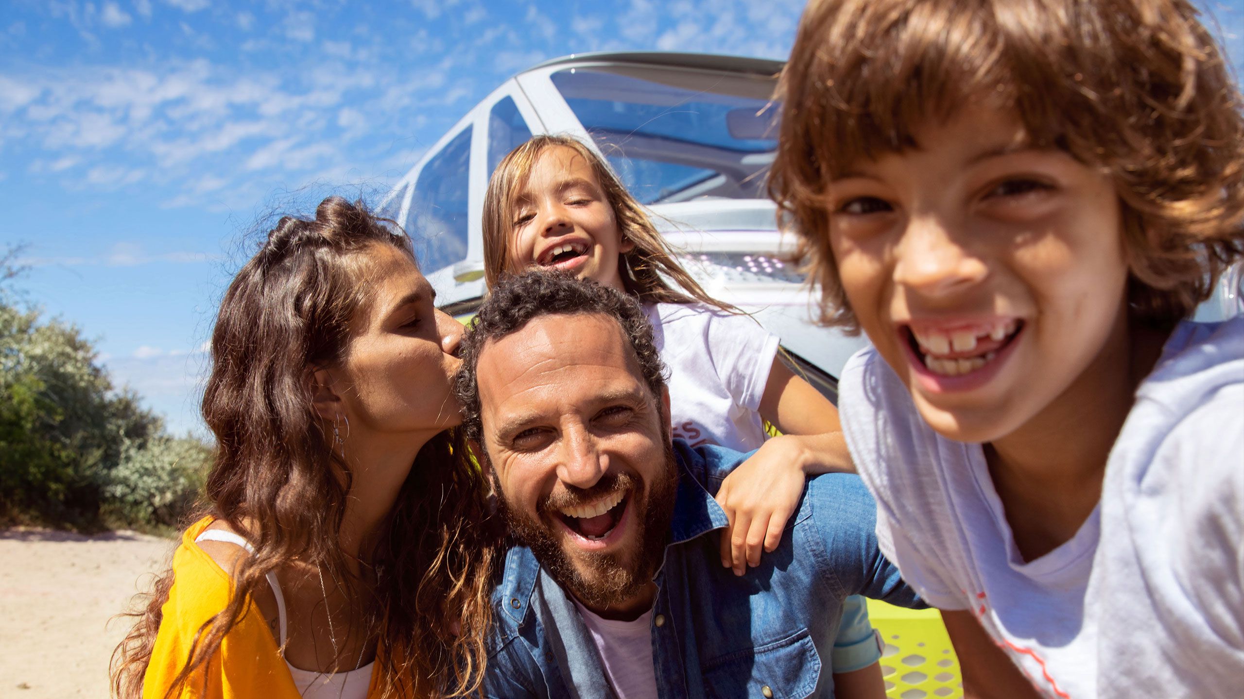 Uma família sorri a tirar uma foto em frente ao VW ID. Buzz