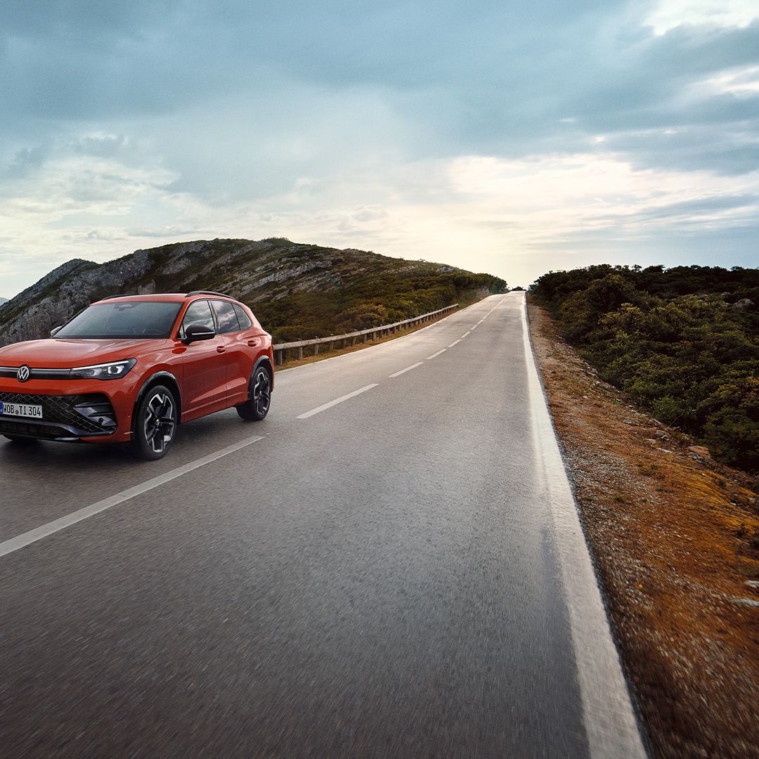 O VW Tiguan vermelho desloca-se ao longo de uma estrada.