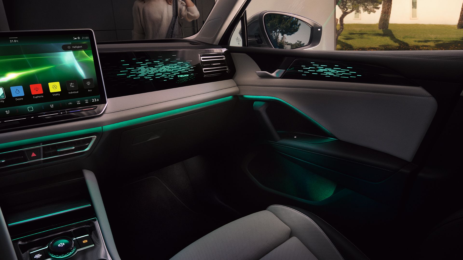 Vista interior do VW Tiguan à noite, o ecrã a cores mostra as definições da iluminação ambiente opcional, o habitáculo é iluminado a verde.