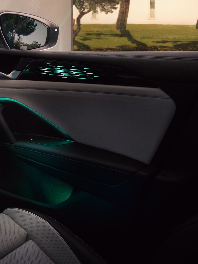 Vista interior do VW Tiguan à noite, o ecrã a cores mostra as definições da iluminação ambiente opcional, o habitáculo é iluminado a verde.