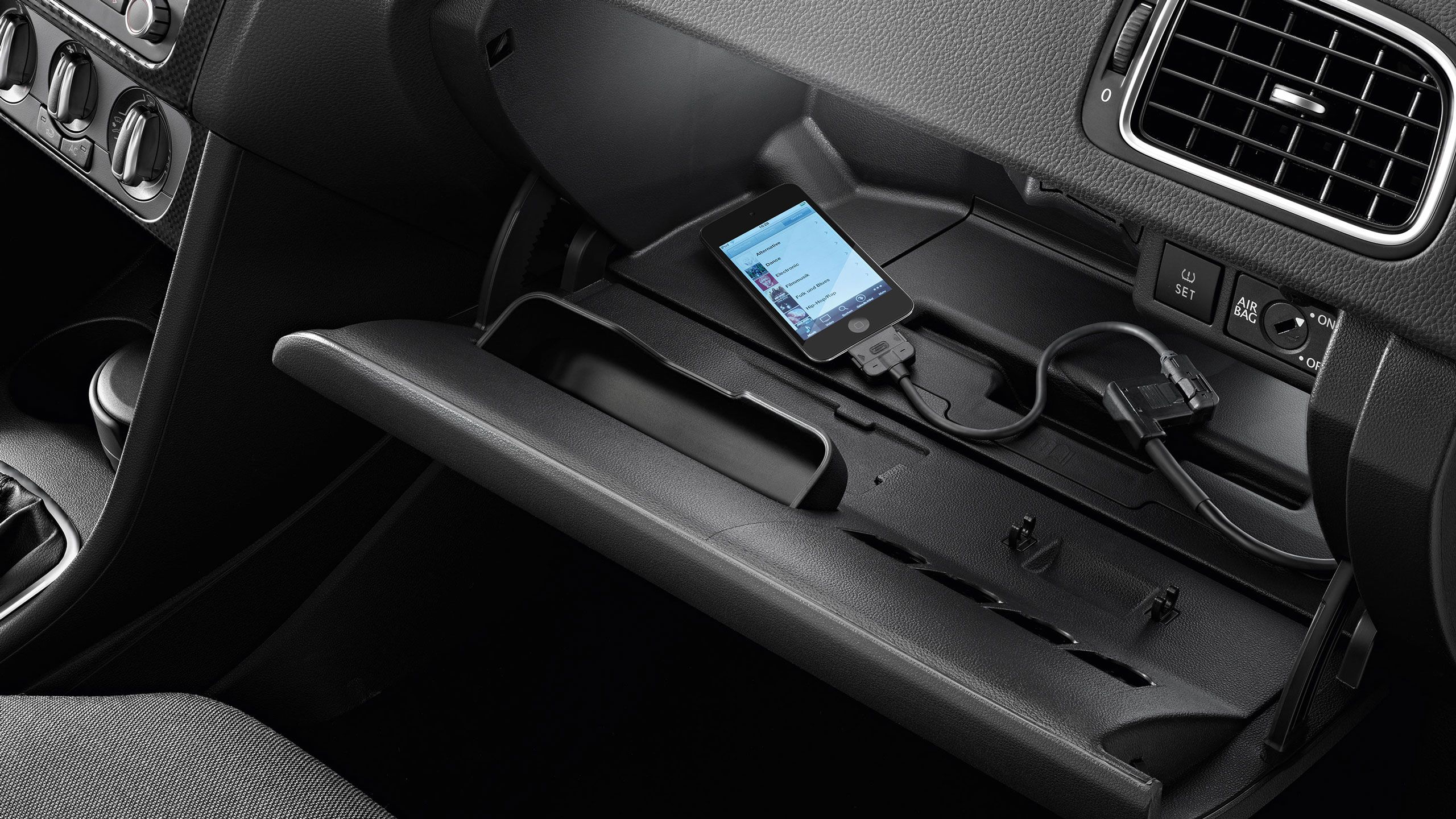 Uma vista detalhada de um smartphone a carregar dentro de um porta-luvas VW Polo 5 - Acessórios interiores Volkswagen