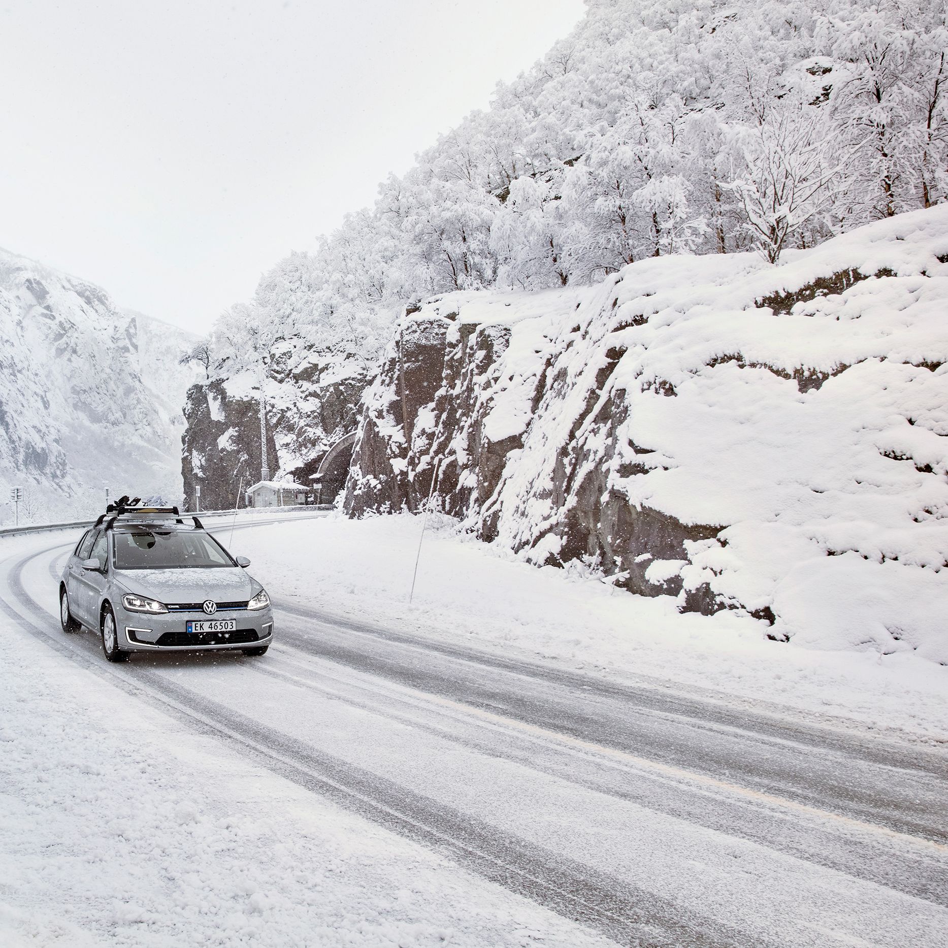 e-Golf com suporte para prancha de snowboard a conduzir através de uma paisagem de montanha com neve