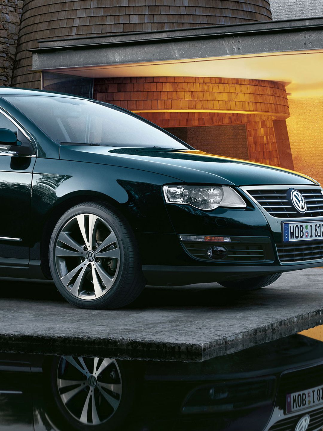 Um automóvel VW Passat B6 preto estacionado ao lado de uma casa iluminada com água à sua volta