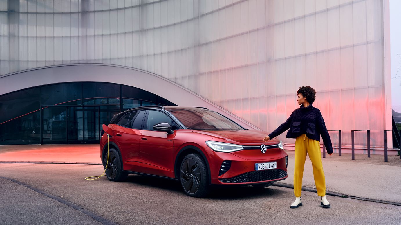 Jovem mulher em frente a um VW ID.4 GTX vermelho