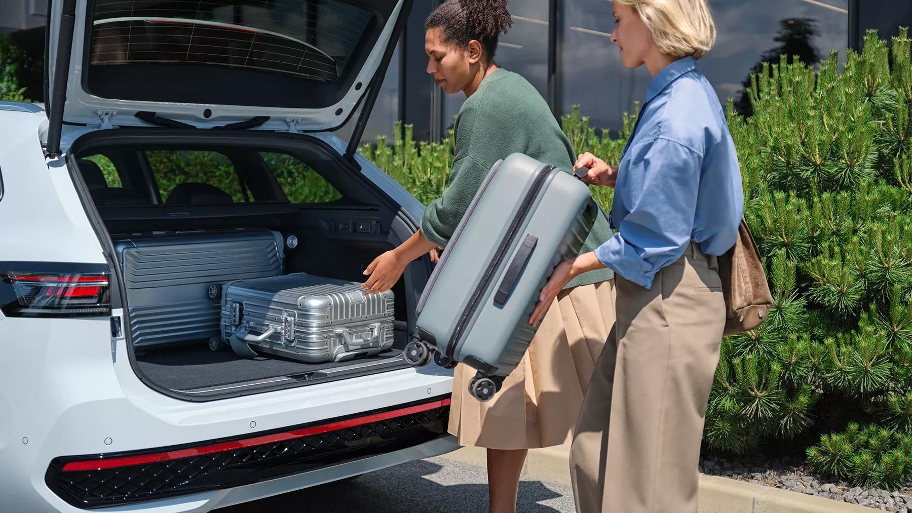 Duas mulheres a carregar bagagem na generosa bagageira do VW Passat.