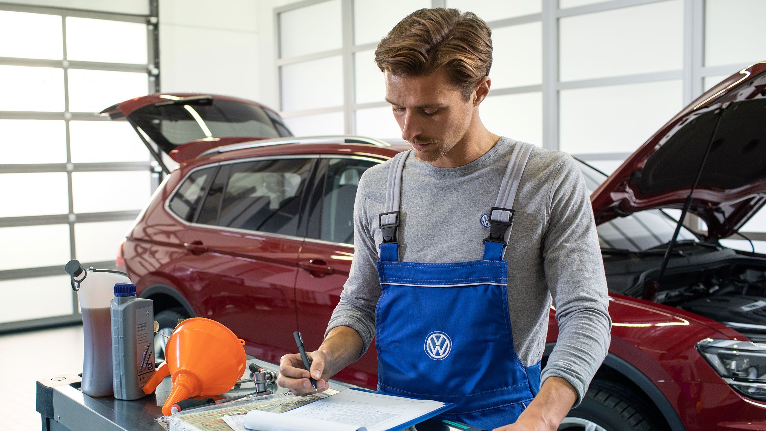 Empregado de serviço da VW verifica um carro com condução a gás natural numa oficina