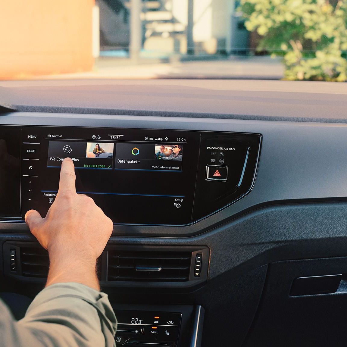 Blick auf das Display im VW Polo mit We Upgrade Funktionen. Ein Mann sitzt am Steuer und bedient das Display. 