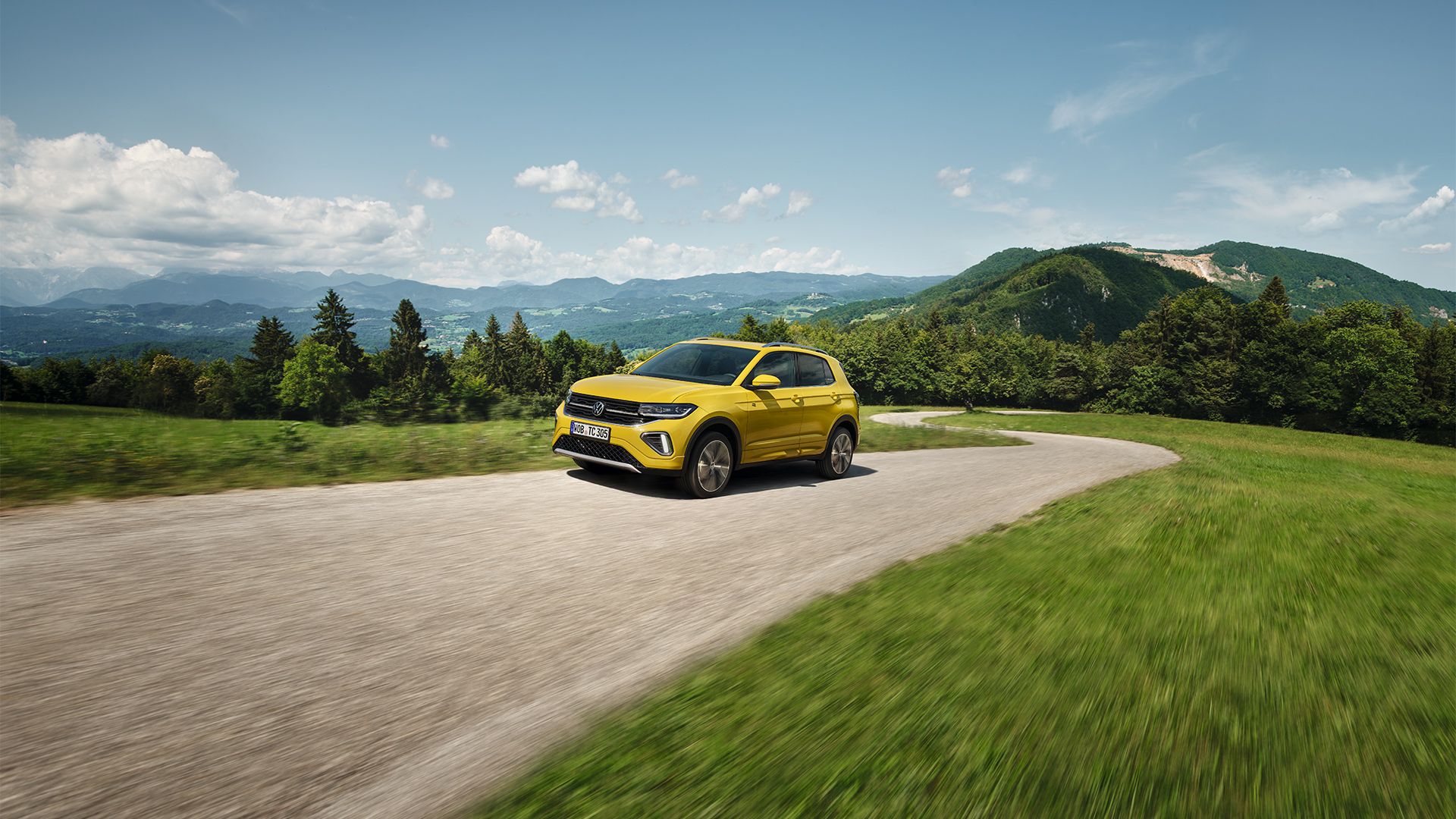 Um VW T-Cross amarelo numa estrada com paisagem montanhosa.