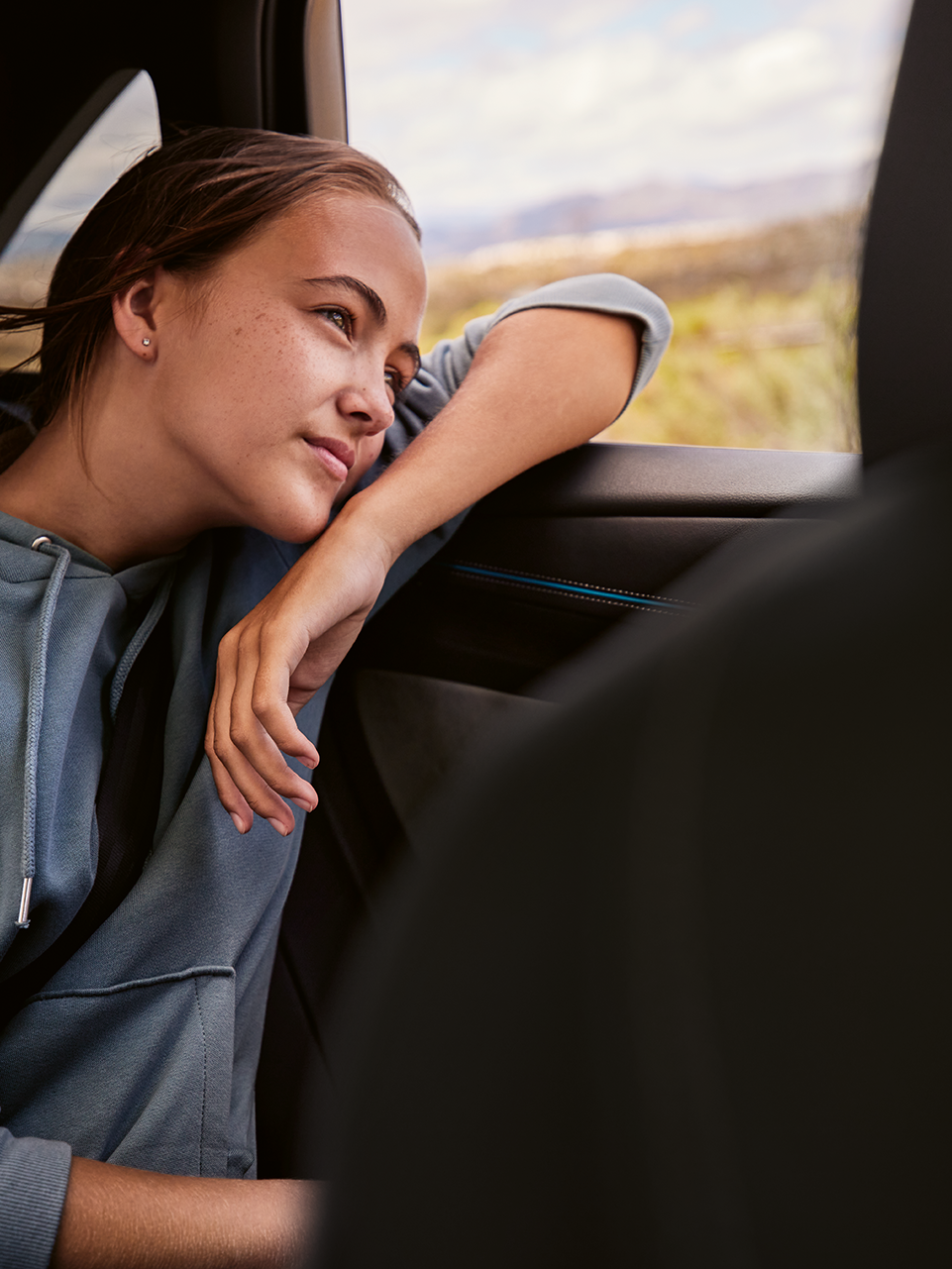 Mulher jovem no banco traseiro de um VW ID.7 olhando para fora da janela.