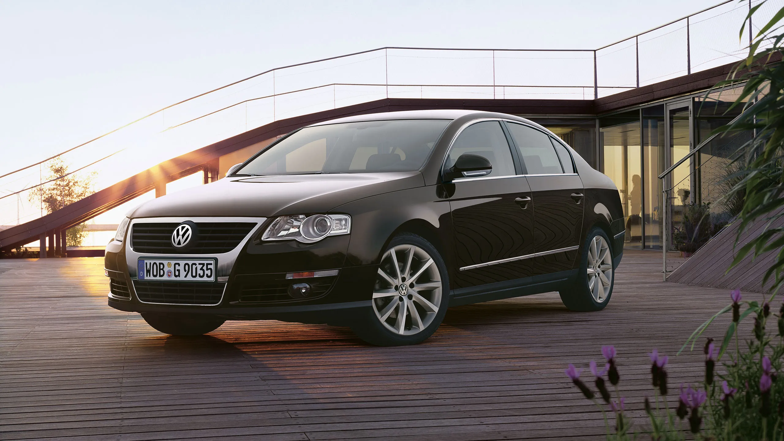 Um VW Passat B6 preto estacionado num terraço de madeira.