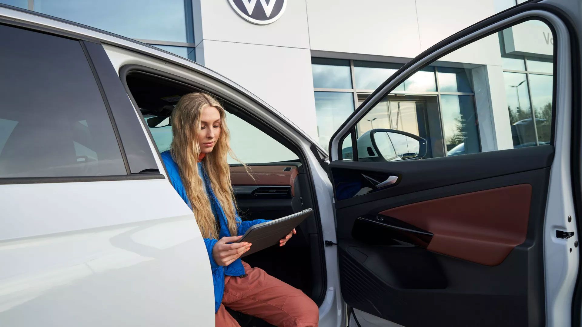 Eine Frau sitzt bei geöffneter Fahrzeugtüre in einem VW ID.