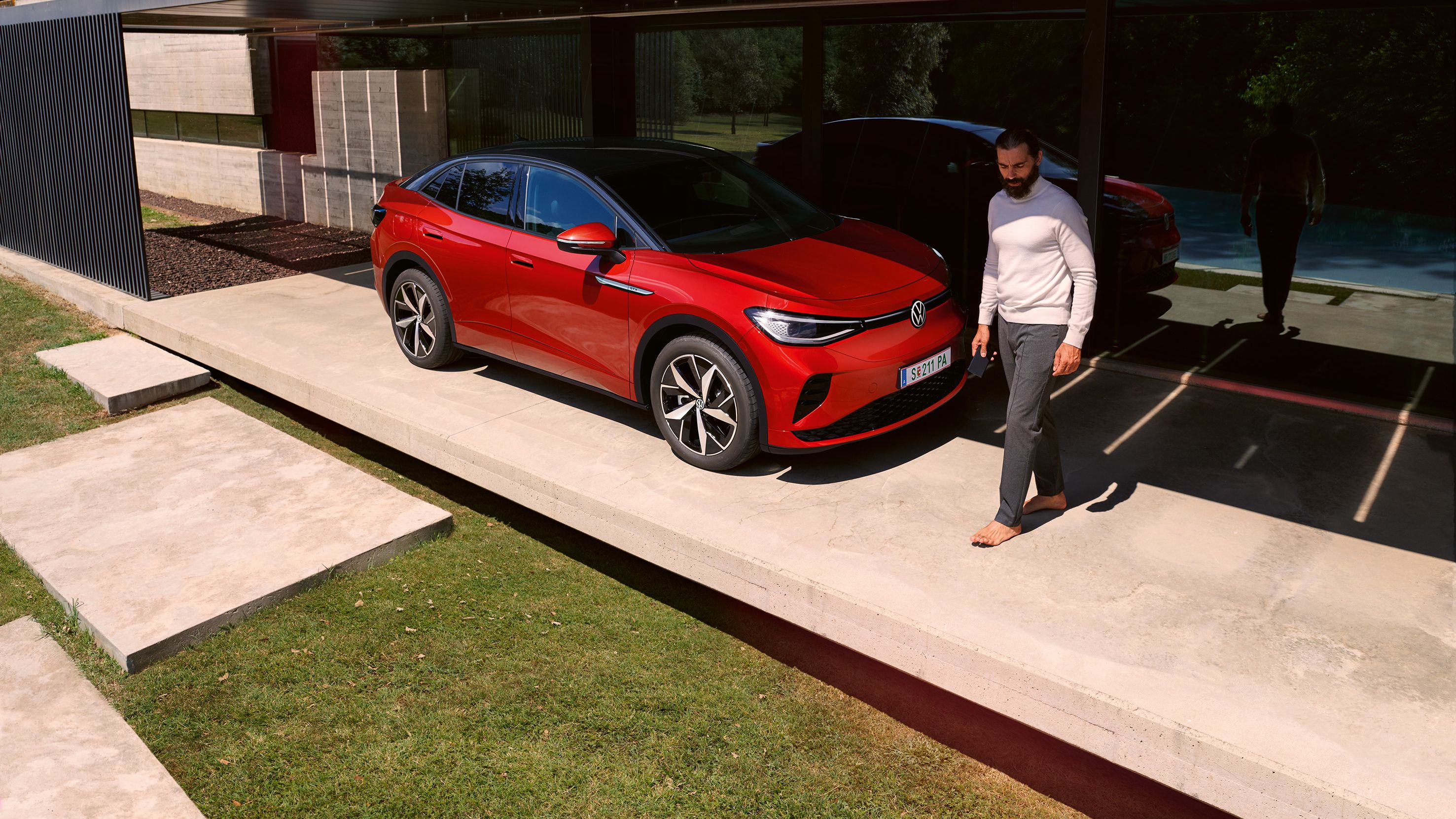 VW ID.5 GTX vermelho a estacionar em frente de uma casa. Um homem vai a passar.