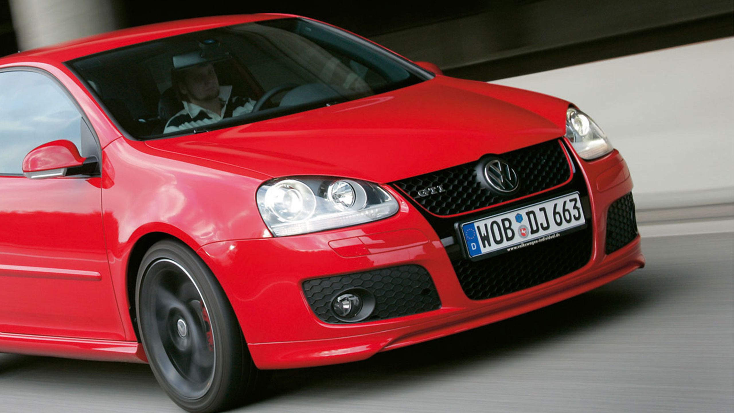 Um homem conduz num VW Golf V GTI vermelho